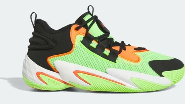 Side view of a green, orange, and black adidas shoe.